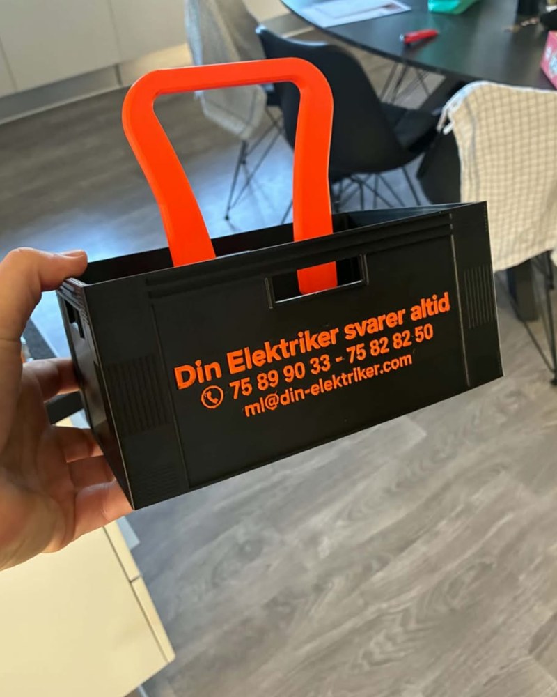 3D-printet ølkasse i sort med orange håndtag og tekst